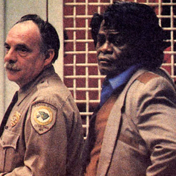 James Brown, serious in a suit, with the bailiff
