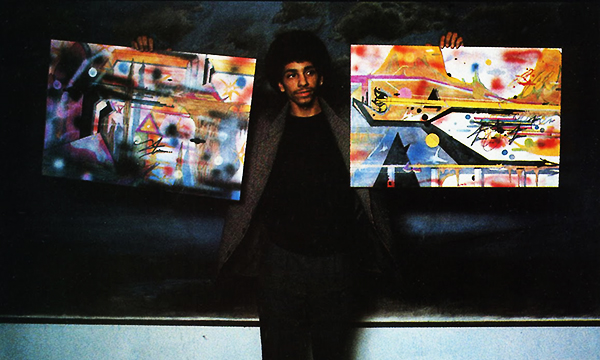 Rammellzee holds up a pair of his paintings