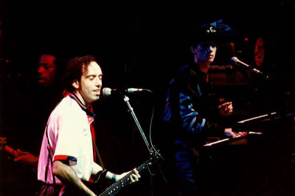 Mick Jones strums the guitar on stage as B.A.D. play on in the background