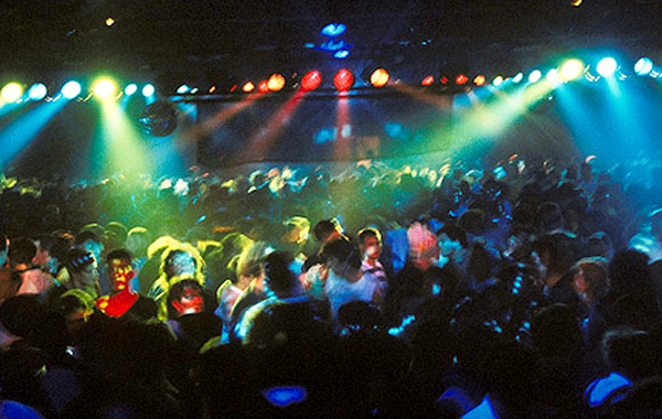 A massive crowd dances at an indoor rave