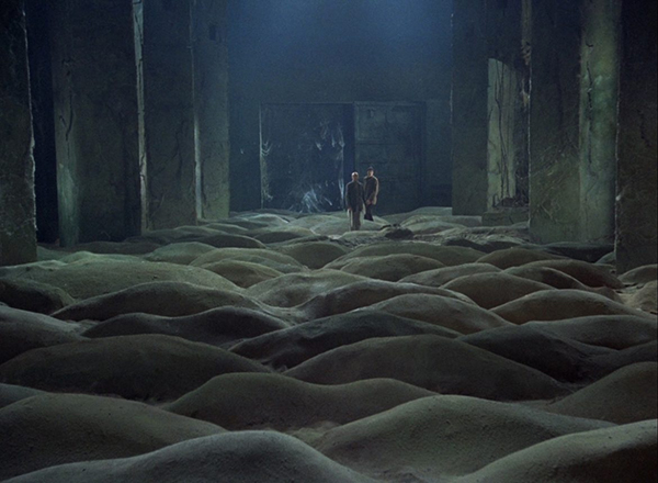 A scene taken from the movie Stalker, where the trio must cross a dune-covered empty room.